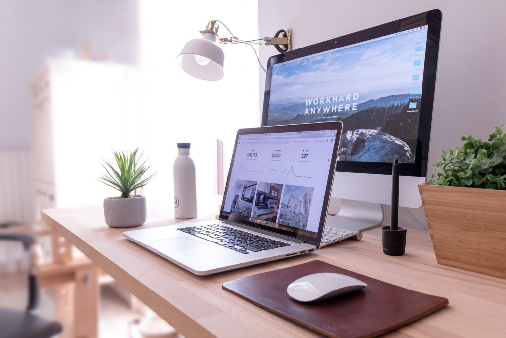 home office desk with computer and task lighting near a bright window